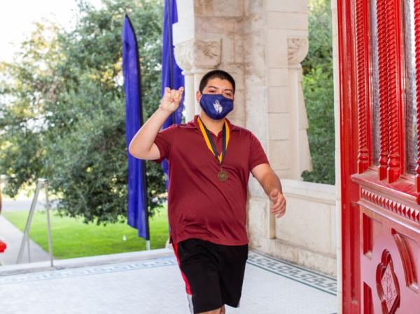 student with blue COVID mask walking on campus 