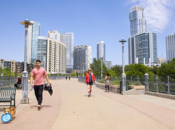 skyline of downtown austin with several people crossing a bridge 