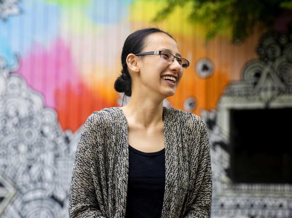 Murphy Chen stands in front of a colorful mural in downtown Austin.