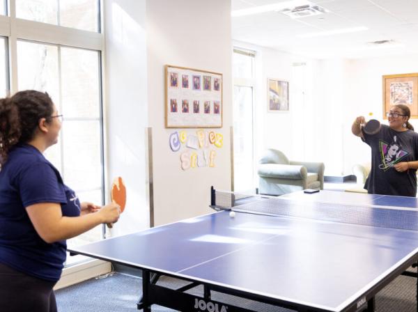 2 students playing ping pong in a residence hall 