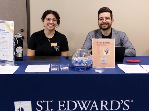 Two OIT staff members sit at a table during an event.