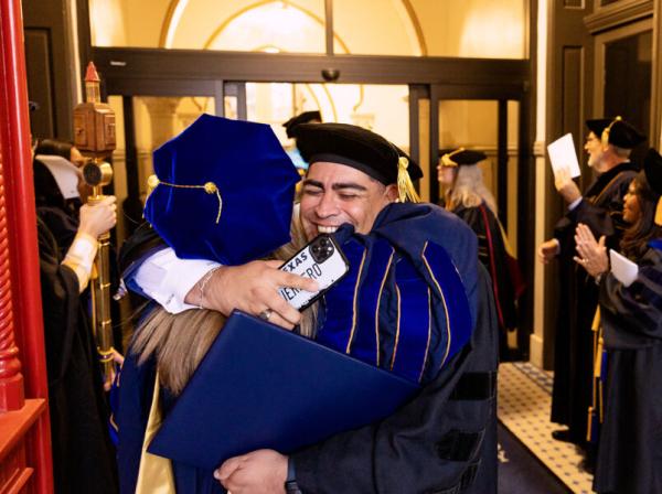 student hugging the president at graduation 