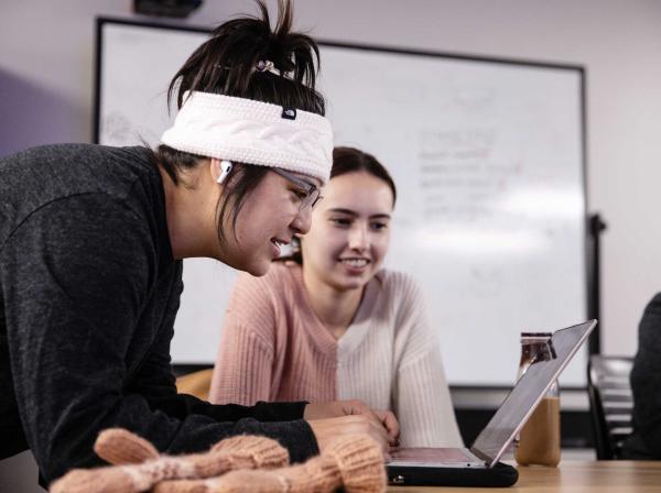 A student types on a computer as another student looks on.