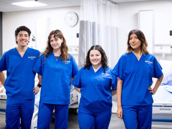 4 nursing students in blue scrubs 