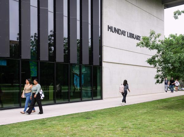 Students walk on a path outside of the Munday Library.