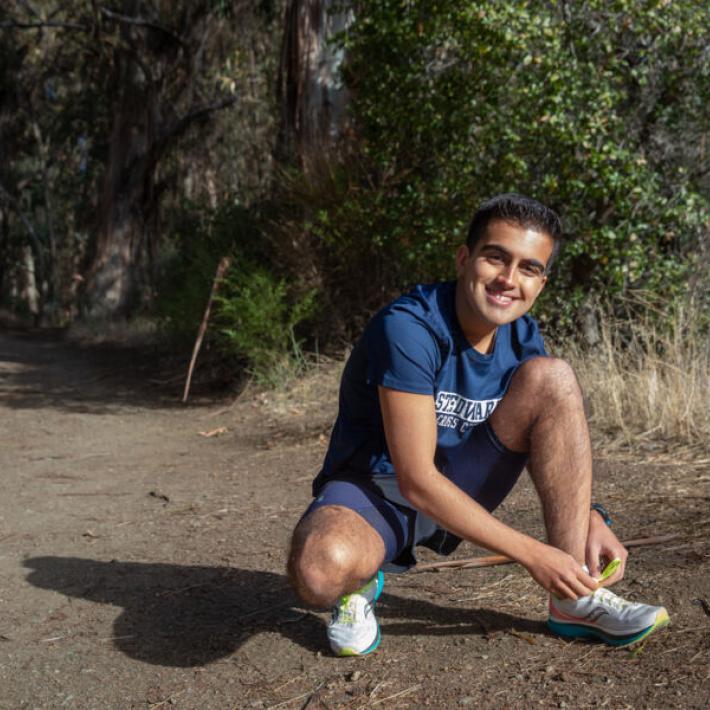 Arrian Ebrahimi tying his shoe on a running trail 