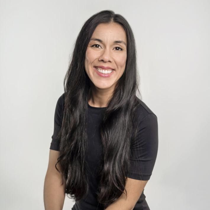 A woman with black hair in a black dress poses for the camera