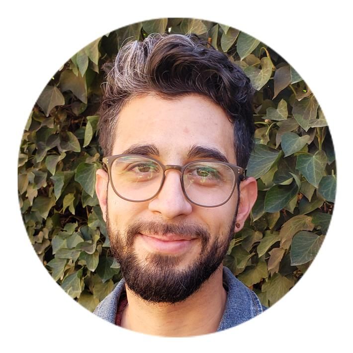 Close-up headshot of a man with black hair, a beard, and glasses