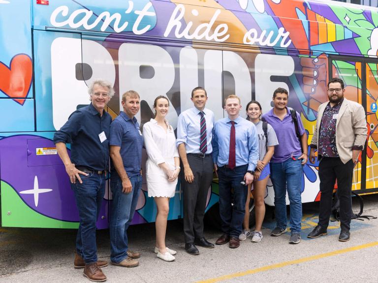 Civics Lab class in front of a colorful pride bus 