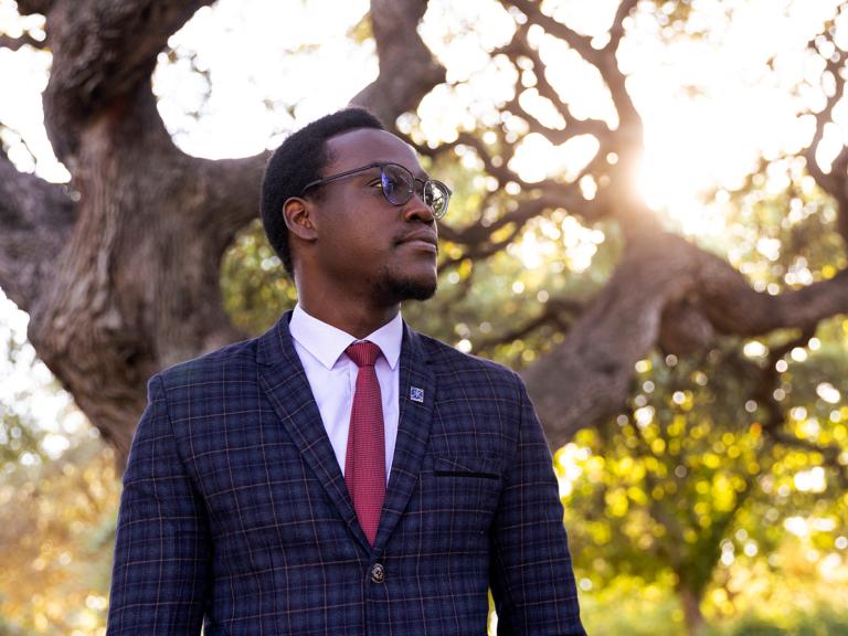 Student, Emmanuel Epau, poses in front of Sorin Oak