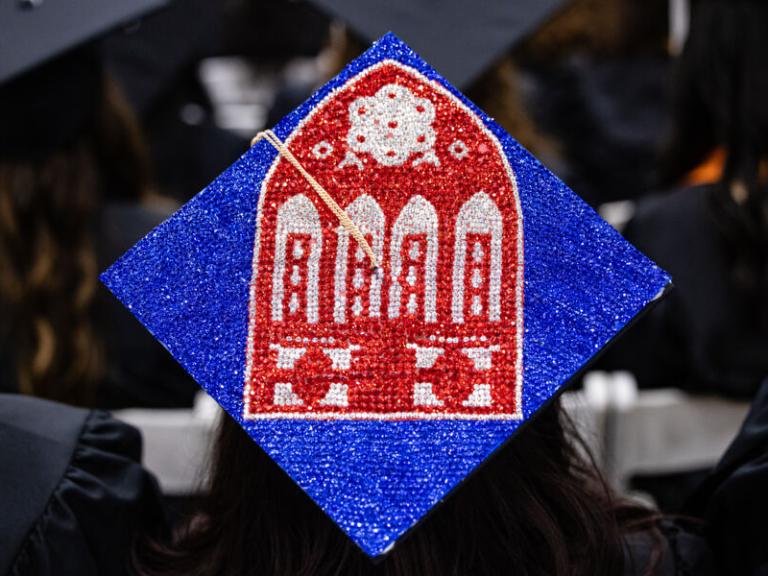 Graduating senior creates Main Building Red Doors image on their cap for December 2024 Commencement.