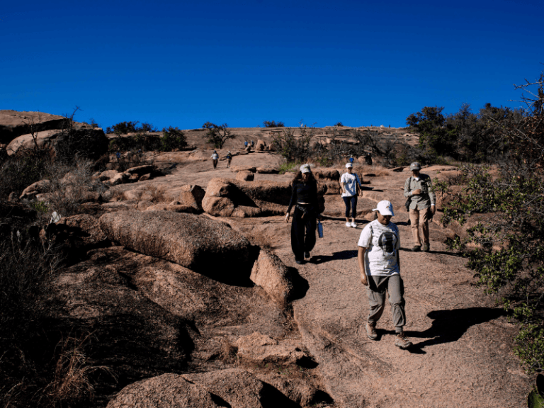 Students hike down Enchanted Rock on a Texas Ecology class field trip