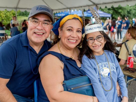 A happy family poses outside under an event tent