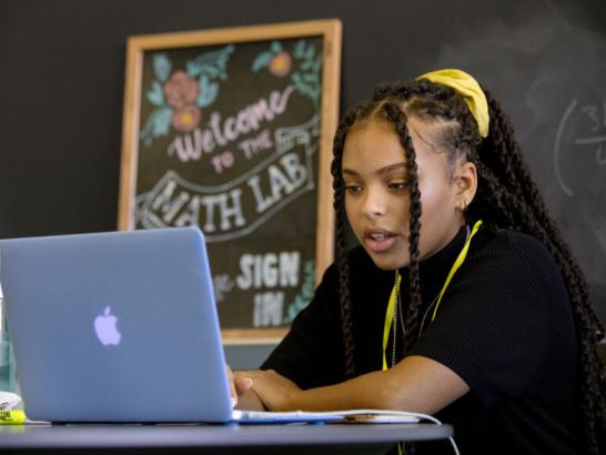 A peer tutor meets with a student virtually on their laptop in the math lab.