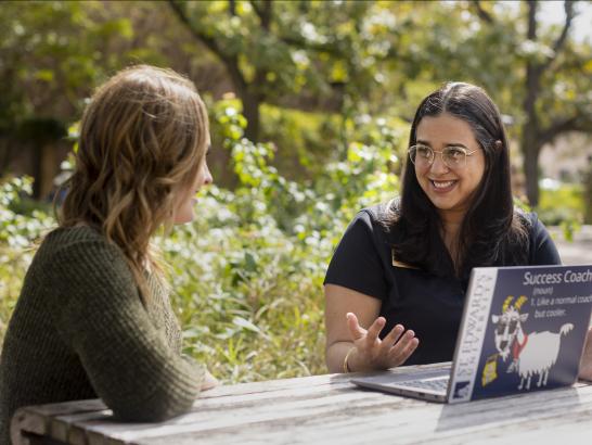 A student meets with a success coach at a patio table.