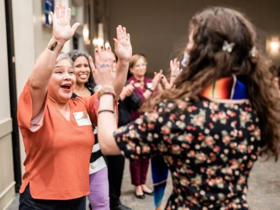 A human resources staff member high fives a student during a graduation celebration.