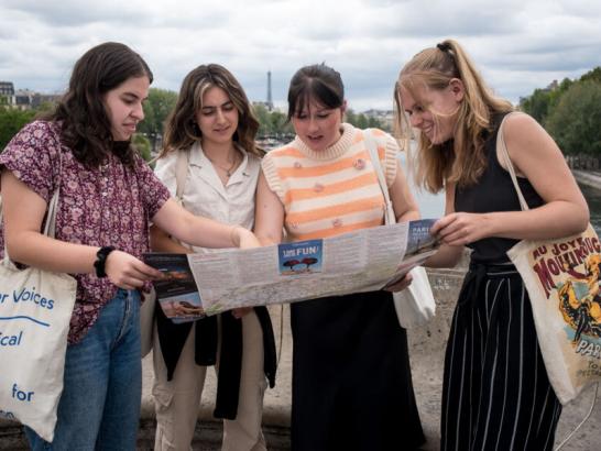 Four students gather around a map and point to it while exploring Paris, France during their study abroad trip.