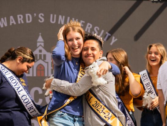 Two students on the homecoming court embrace on stage after being crowned homecoming queen and homecoming king.