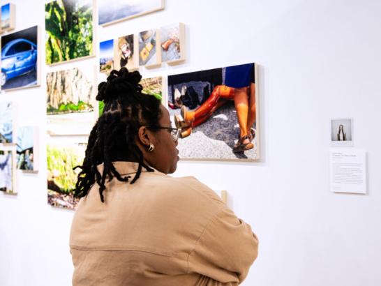 A student reads a biography of a student artist and views their work in the Fine Arts Gallery.