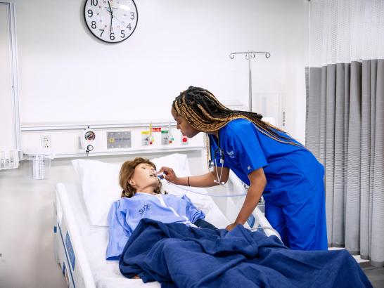 A student in scrubs administers simulated care to a manikin in the new lab space at St. Edward's