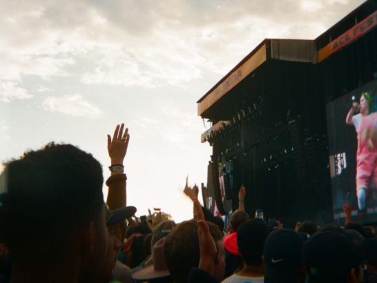 A large crowd in front of a stage where Billie Eilish is singing