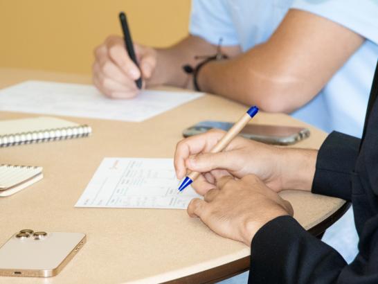 Two students take notes at a table.