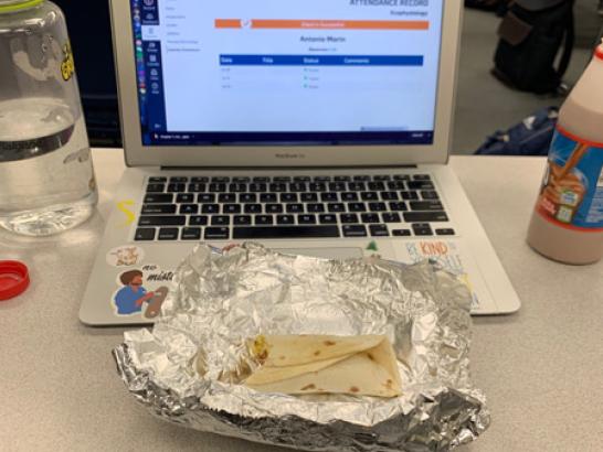 A laptop with a half eaten burrito in front of it