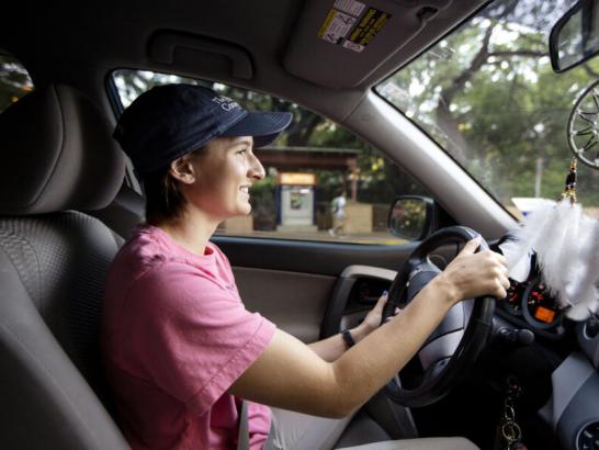 A student driving in a car on campus