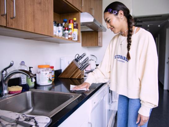 Student cleaning their kitchen area in their apartment at St. Edward's University