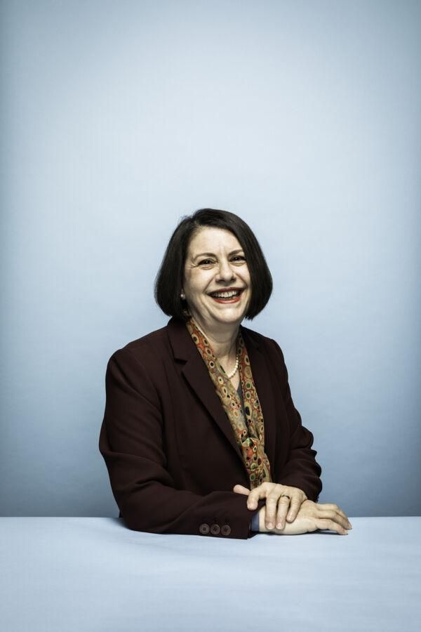 A portrait of Sharon Nell sitting in front of a light blue backdrop.