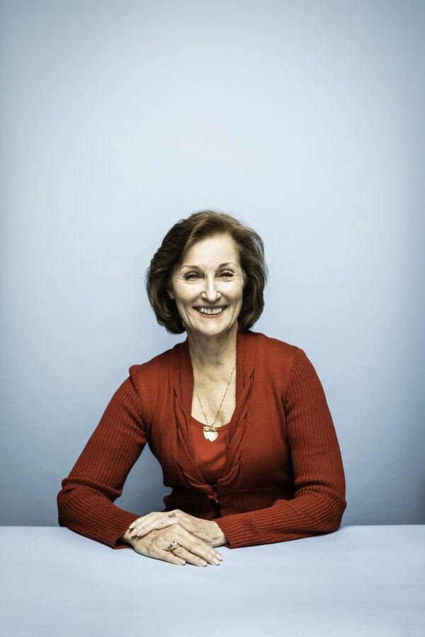 A portrait of Brenda Vallance sitting in front of a light blue backdrop.