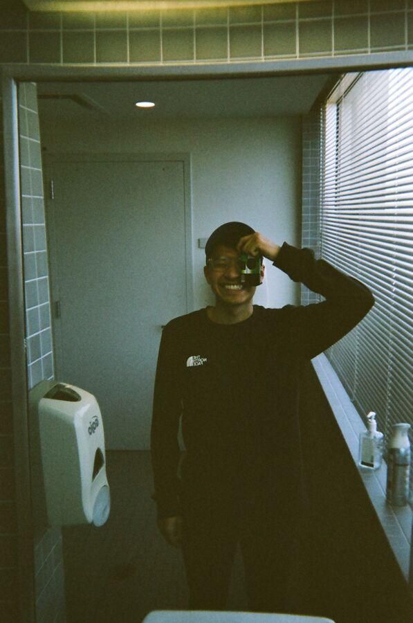 Joshua Rios takes a mirror selfie in the bathroom with a disposable camera.