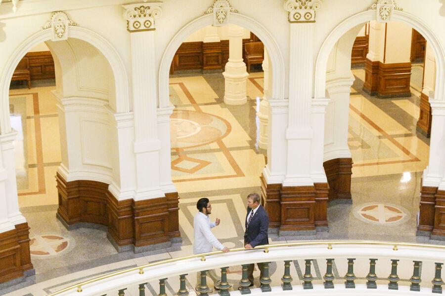 Skylar Garza and David Thomason stand on one of the elevated levels in the rotunda of the Texas State Capitol.