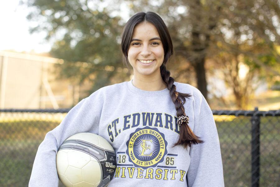 A student wearing a St. Edward's sweater holding a soccer ball