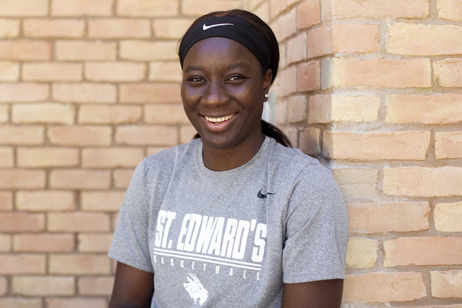 The image shows a person wearing a grey t-shirt with the "St. Edward's" university name and logo, along with the Nike brand symbol. The individual is standing against a brick wall background.