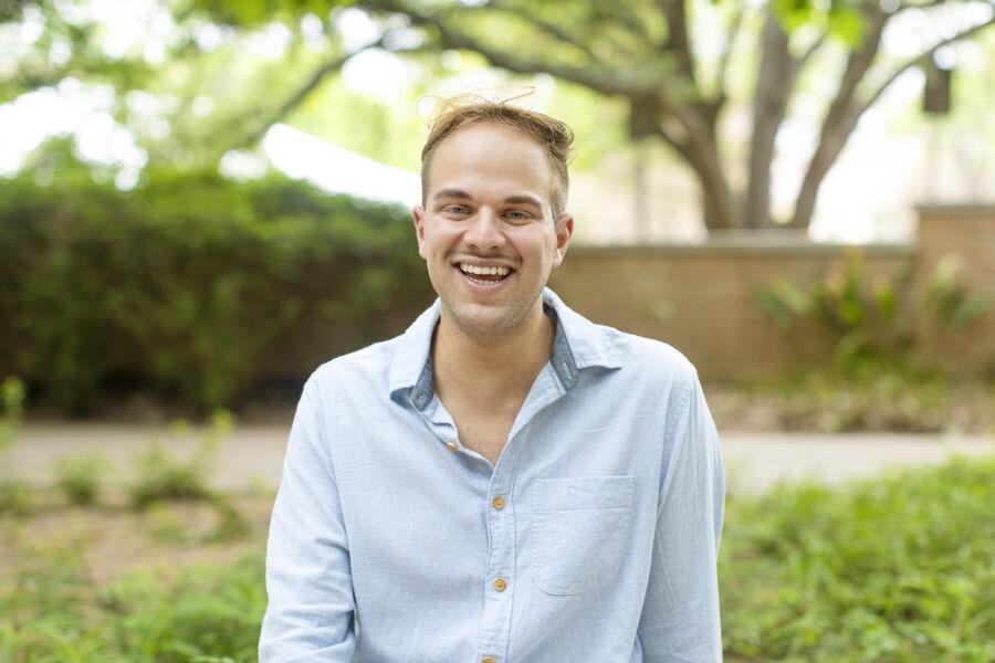 A man in a blue shirt smiling at the camera outside