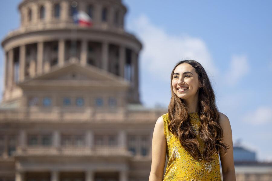 Michelle Flores stands outside of the Texas State Capitol with the building in the background.