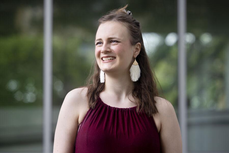 A woman in a maroon dress and dangly earrings smiling