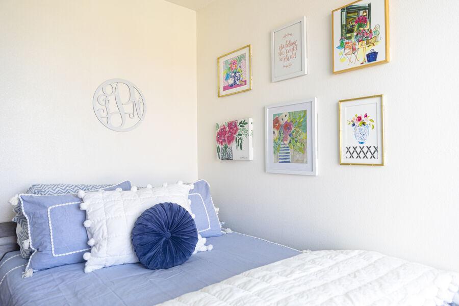 A well-decorated, spacious bedroom with blue bedding and paintings on the wall