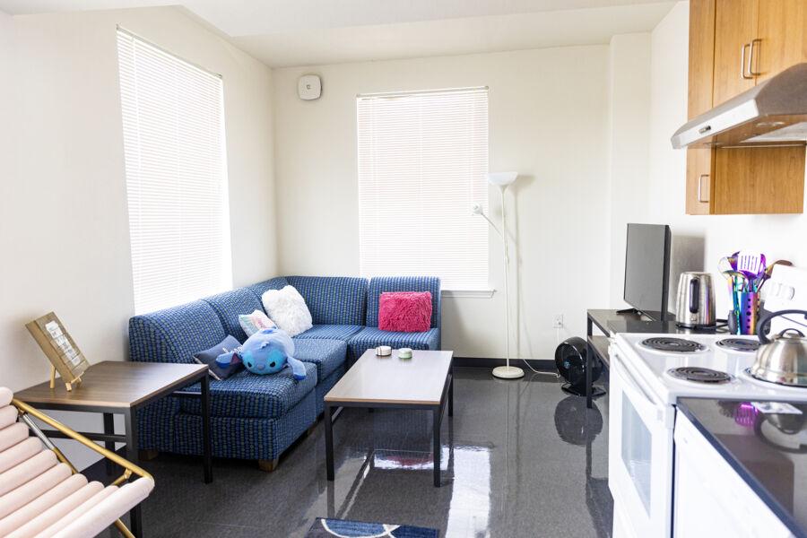 A full living room with a couch, TV, and kitchen space with a stove and countertops