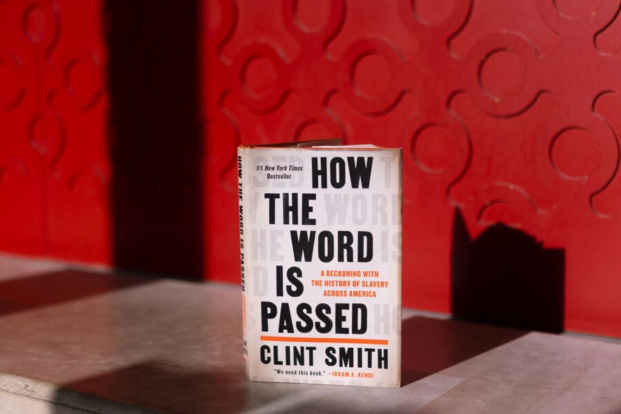 The image features a book titled "HOW THE WORD IS PASSED" by Clint Smith. The cover, set against a red background with circular cut-outs, displays white and yellow text. The subtitle reads "A Reckoning with the History of Slavery Across America." This book delves into significant historical themes related to American slavery. It's a thought-provoking work that explores the impact of slavery across the nation.