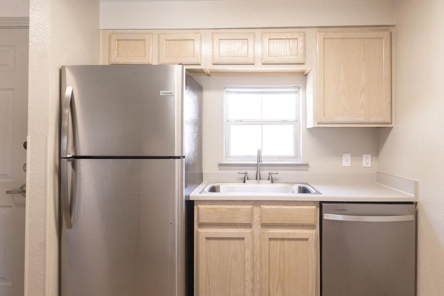 A full kitchen, complete with fridge, dishwasher, and sink. New light wooden cabinets