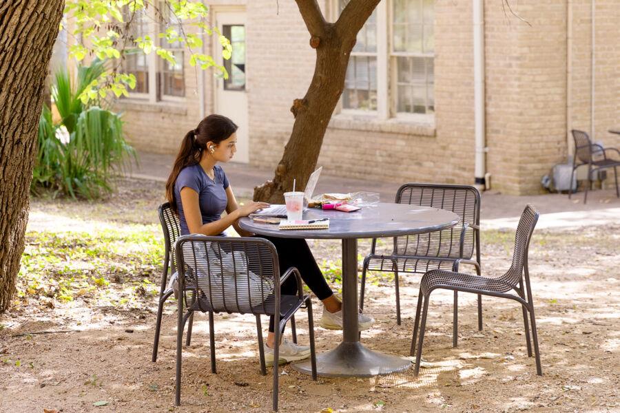 student with their laptop sitting outside