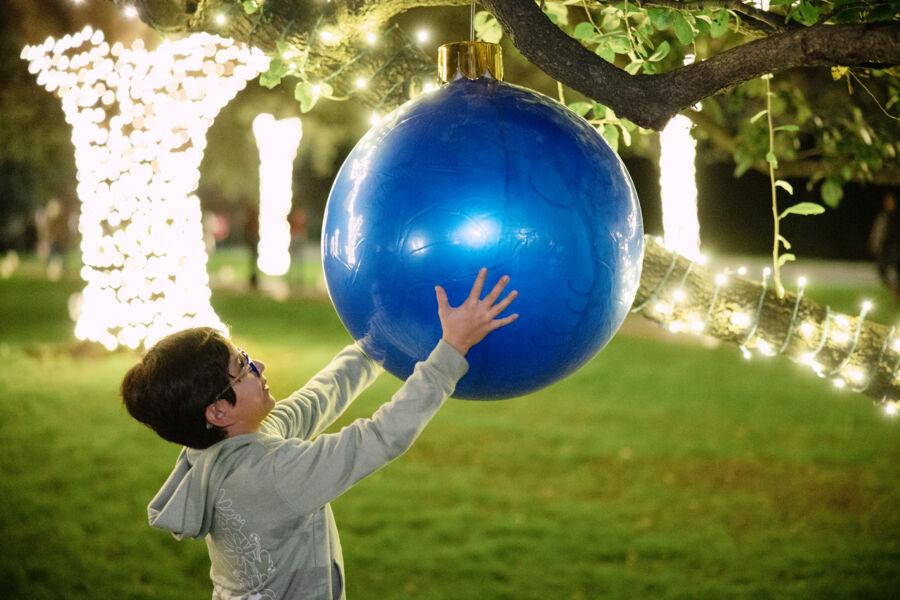 A child holds a larger-than-life blue ornament at Festival of Lights.