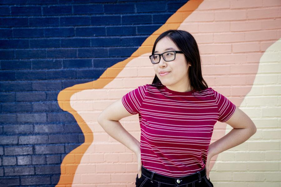 Amy Truong stands in front of a colorful, wavy mural.