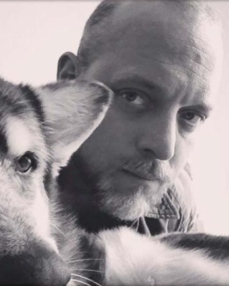 A black and white headshot of a man holding a dog