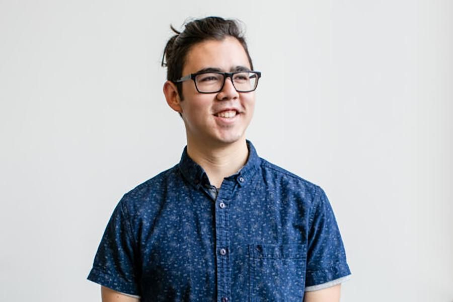 Chris Jackson stands wearing a blue shirt on a grey background.