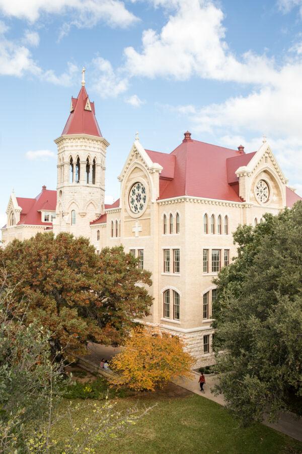 An aerial view of Main Building, surrounded by trees on a sunny day.