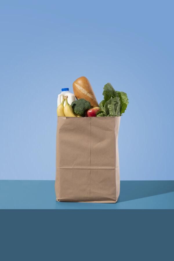 A paper bag full of groceries on a blue background.