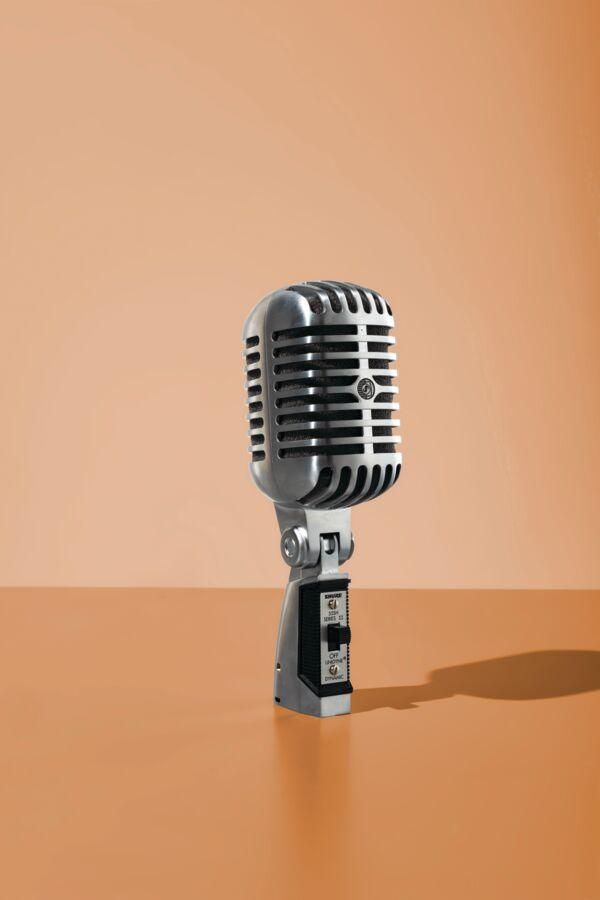 A vintage silver microphone on an orange background.